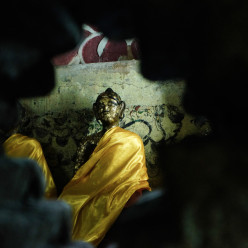 Buddha seen through a port in the wall